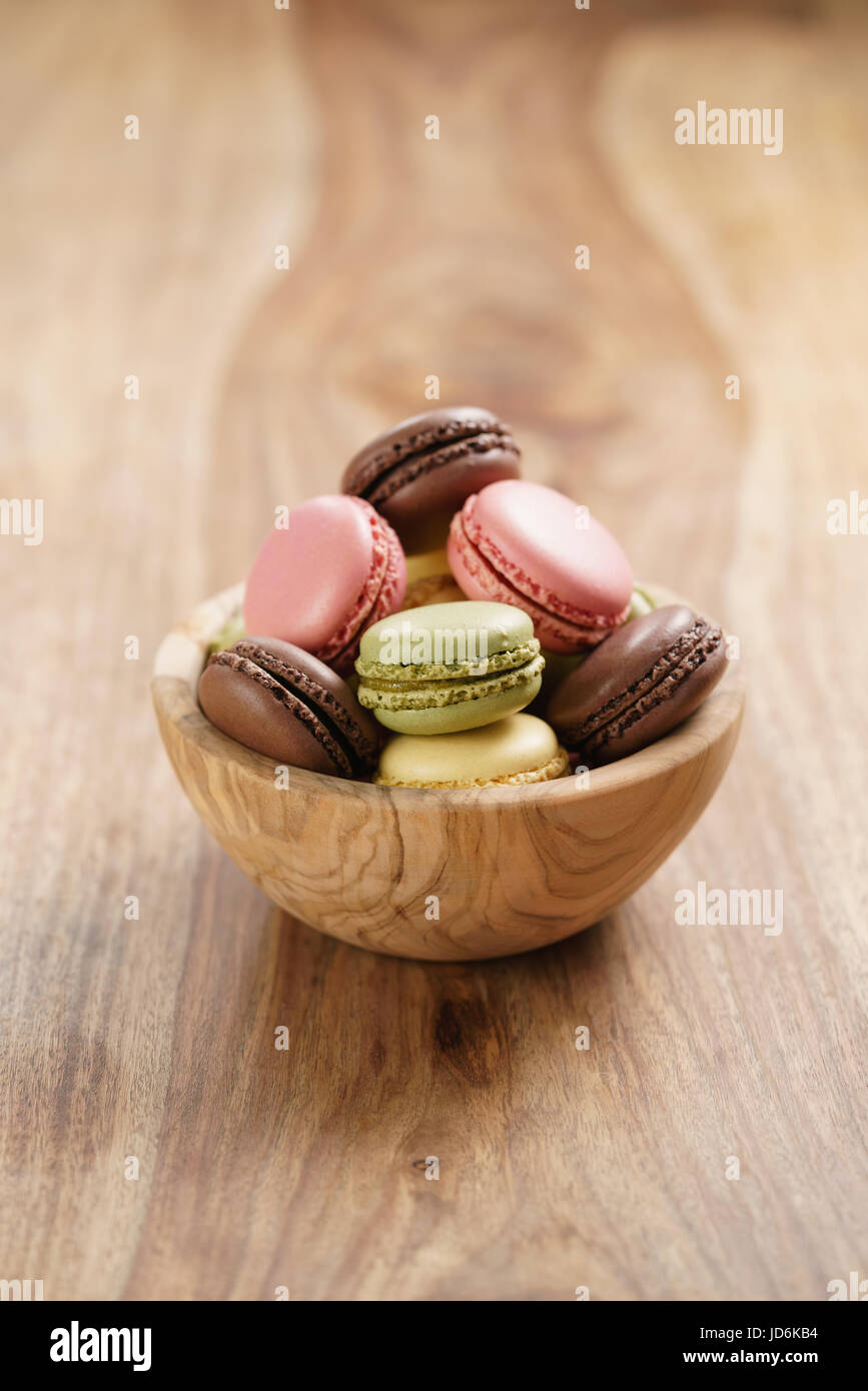 assorted macarons in wood bowl on wooden table Stock Photo