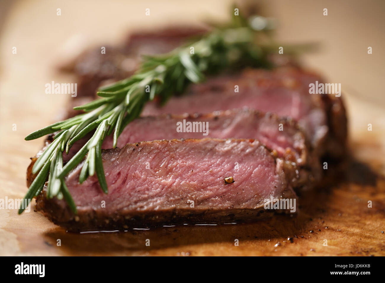 sliced medium rib eye steak with rosemary branch Stock Photo - Alamy