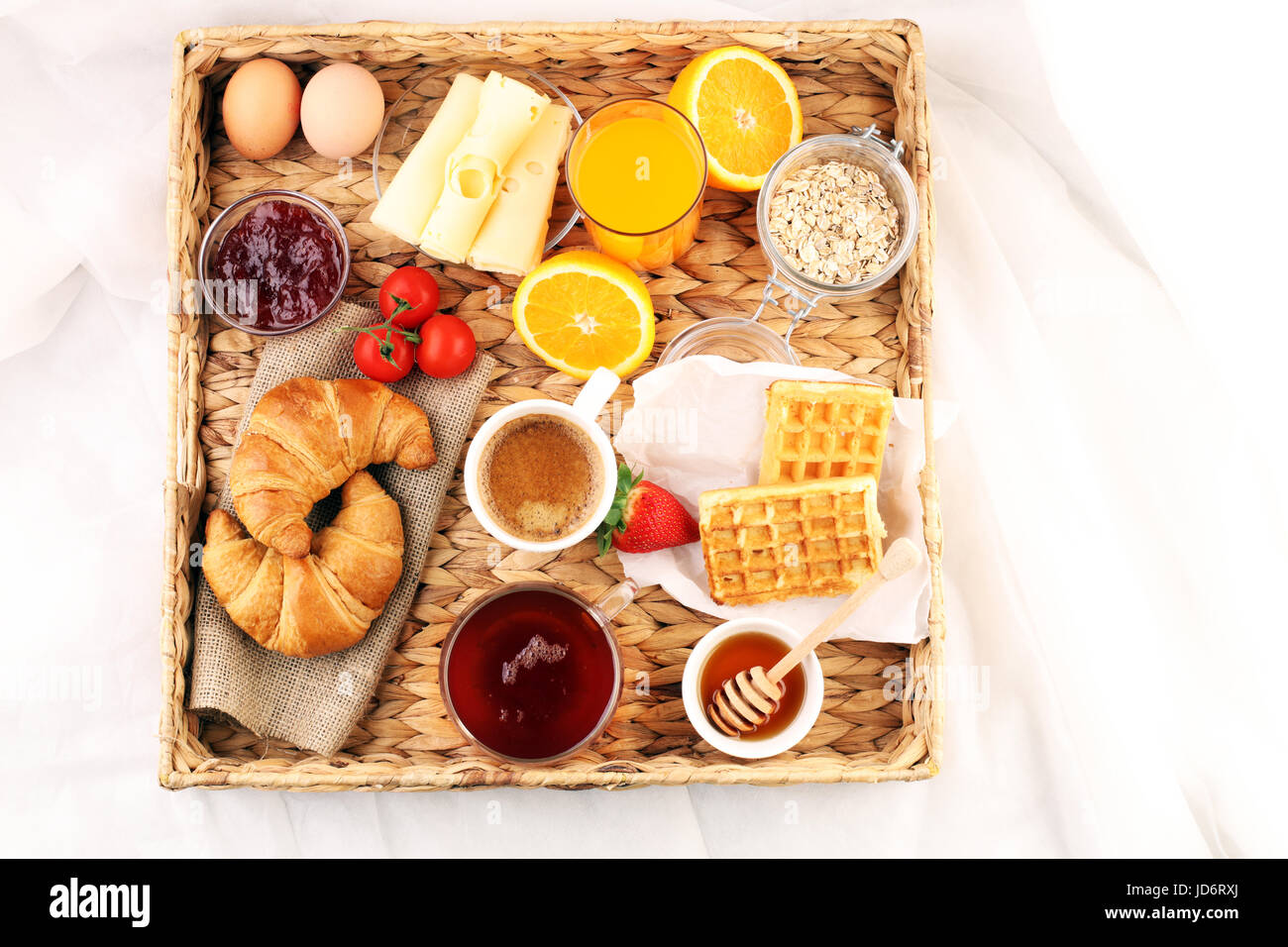 breakfast in bed with fruits and pastries on a tray -waffles, croissants, coffe and juice Stock Photo