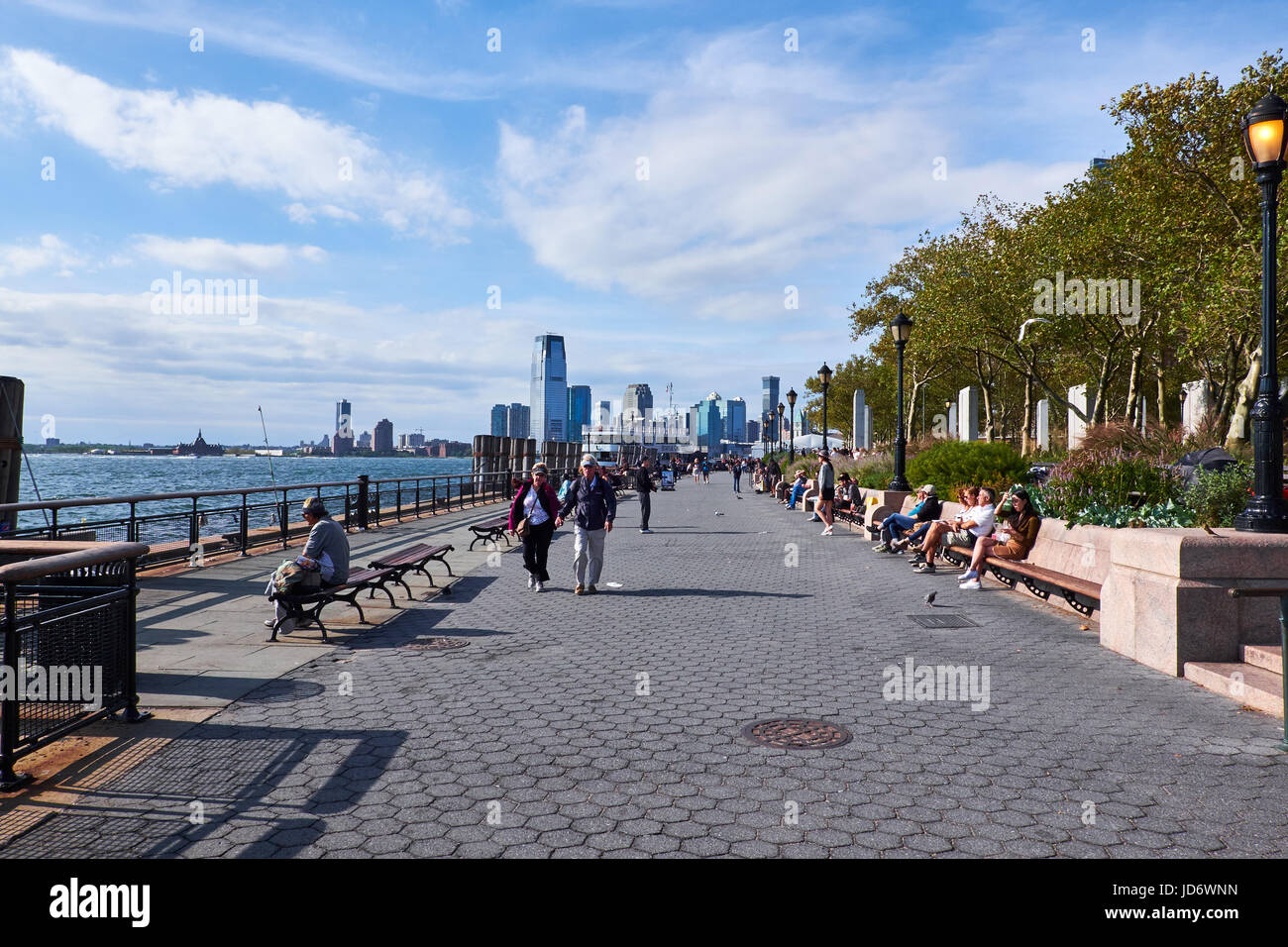 NEW YORK CITY - SEPTEMBER 26, 2016: People strolling and sitting on benches at Battery Park on the south tip of Manhattan Stock Photo