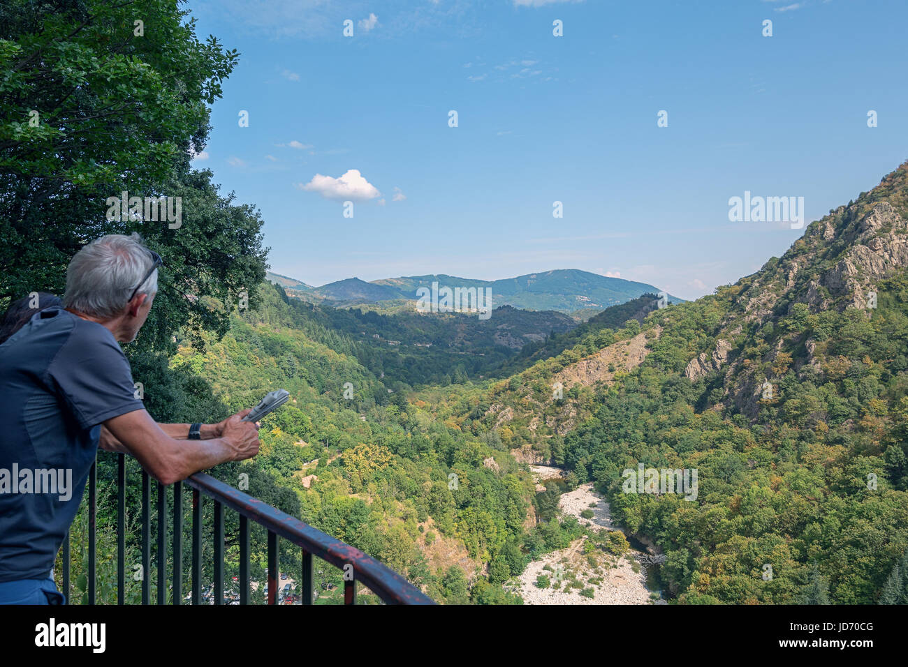 Thueyts, France, september 11,  2016:  Man with newspaper in hands enjoys the view over the valley where the river Ardeche flows Stock Photo
