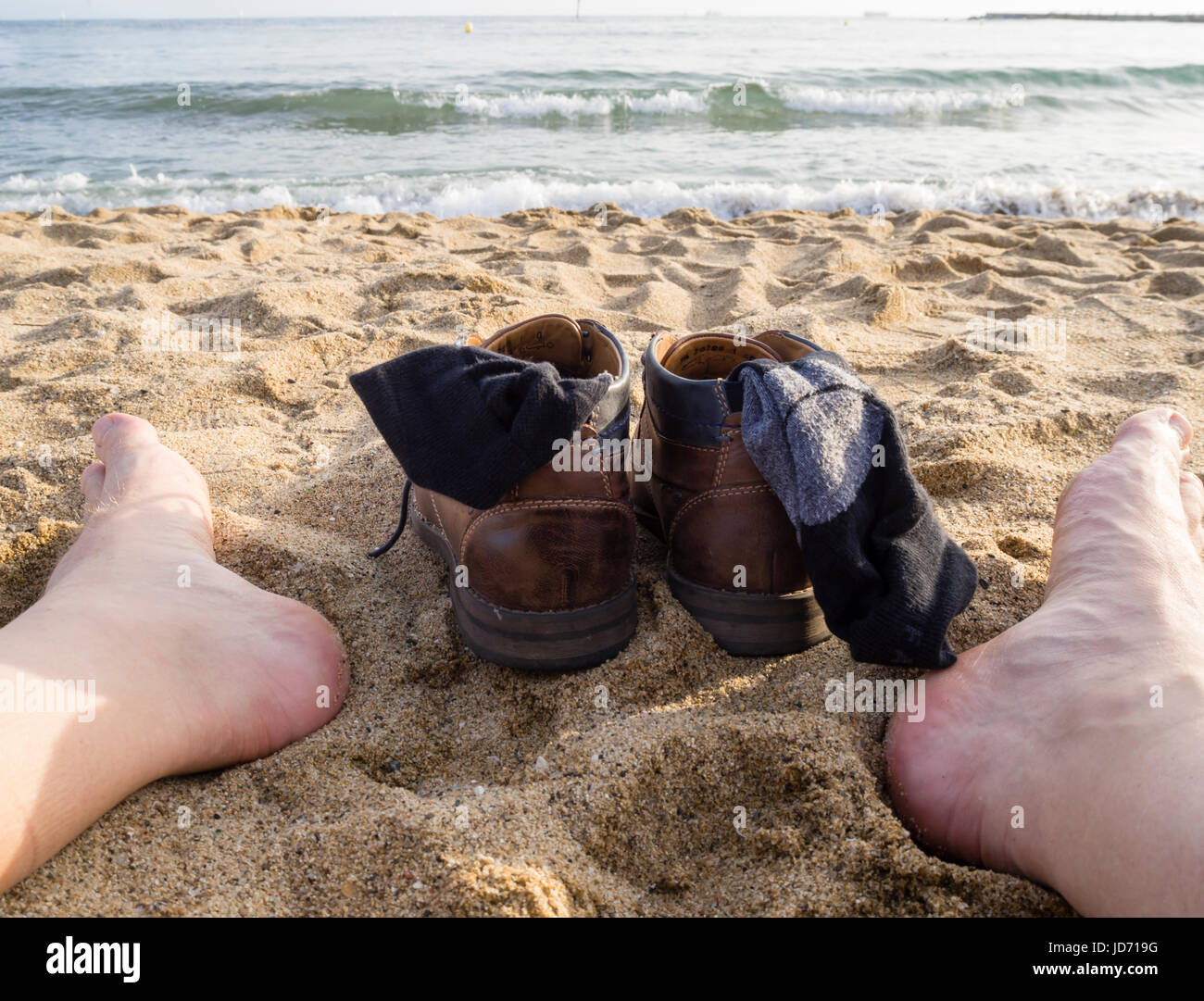 Barefoot feet in the beach sand after taking off shoes. Evening sun