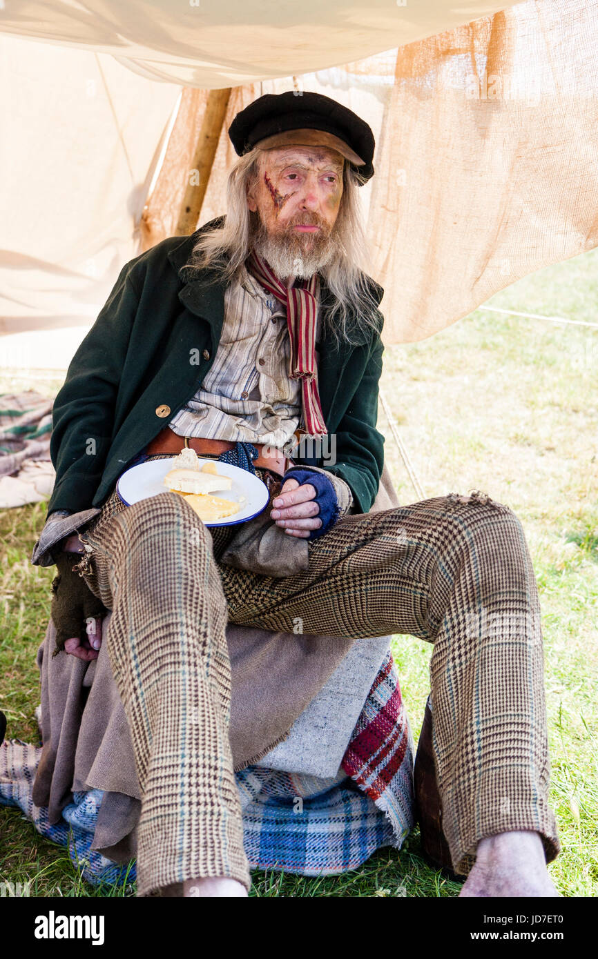 England, Broadstairs, Dickens Week.  'Navy' former Royal Navy sailor and survivor of the battle of Trafalgar, eating a mid-day meal of bread and cheese. Dirty and wearing torn clothes. A member of the Voices From Victorian London Living History group. Stock Photo