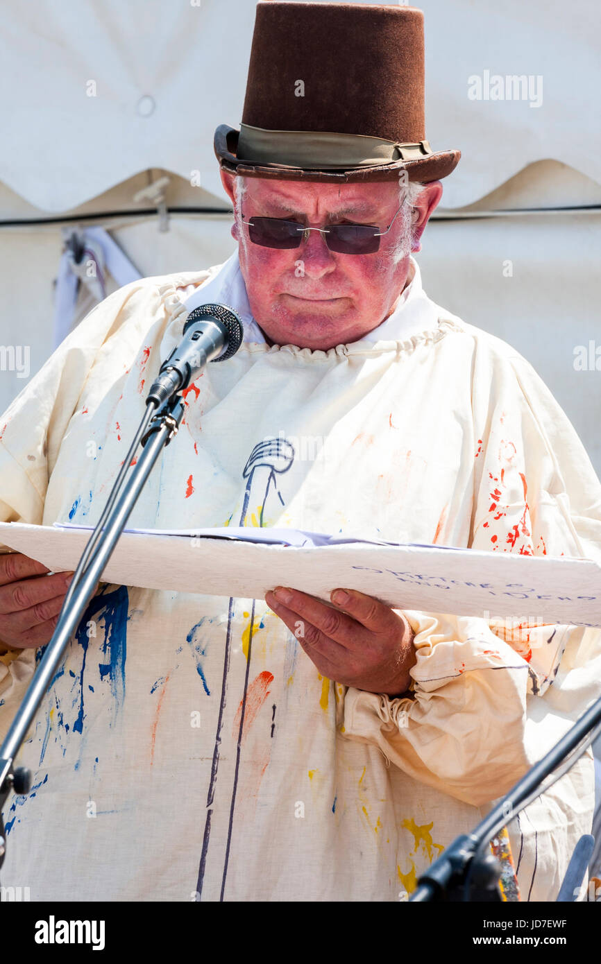 Senior man dressed as the artist Turner, standing while looking down at card he is holding. Wearing dark glasses and top hat with artist smock. Part of the broadstairs Dickens festival. Stock Photo