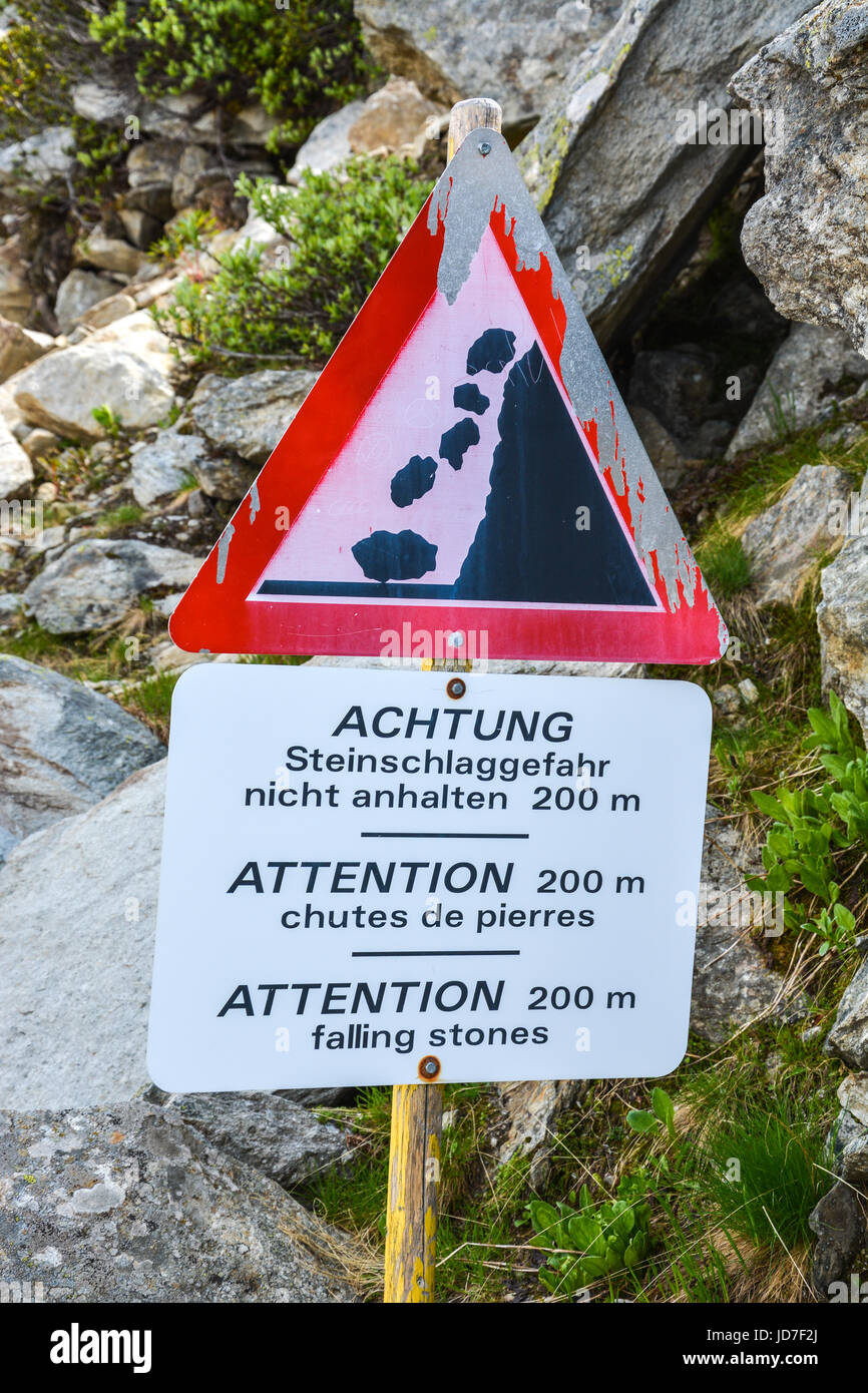 A warning sign about falling stones in the mountains in different languages Stock Photo