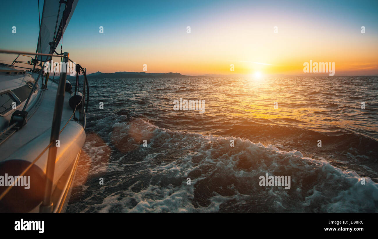 Slide sailing yacht through the waves of the sea during sunset Stock ...