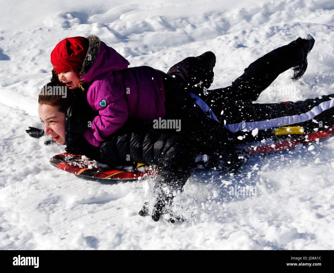 A young child riding on the back of an adult on a sledge Stock Photo