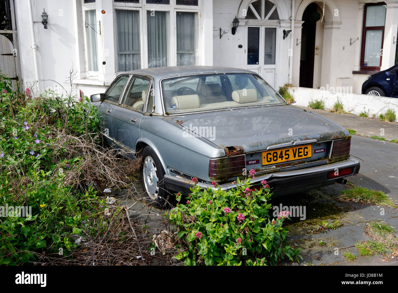 An old Jaguar XJ6, abandoned and rusting in a driveway in Clacton, Essex Stock Photo