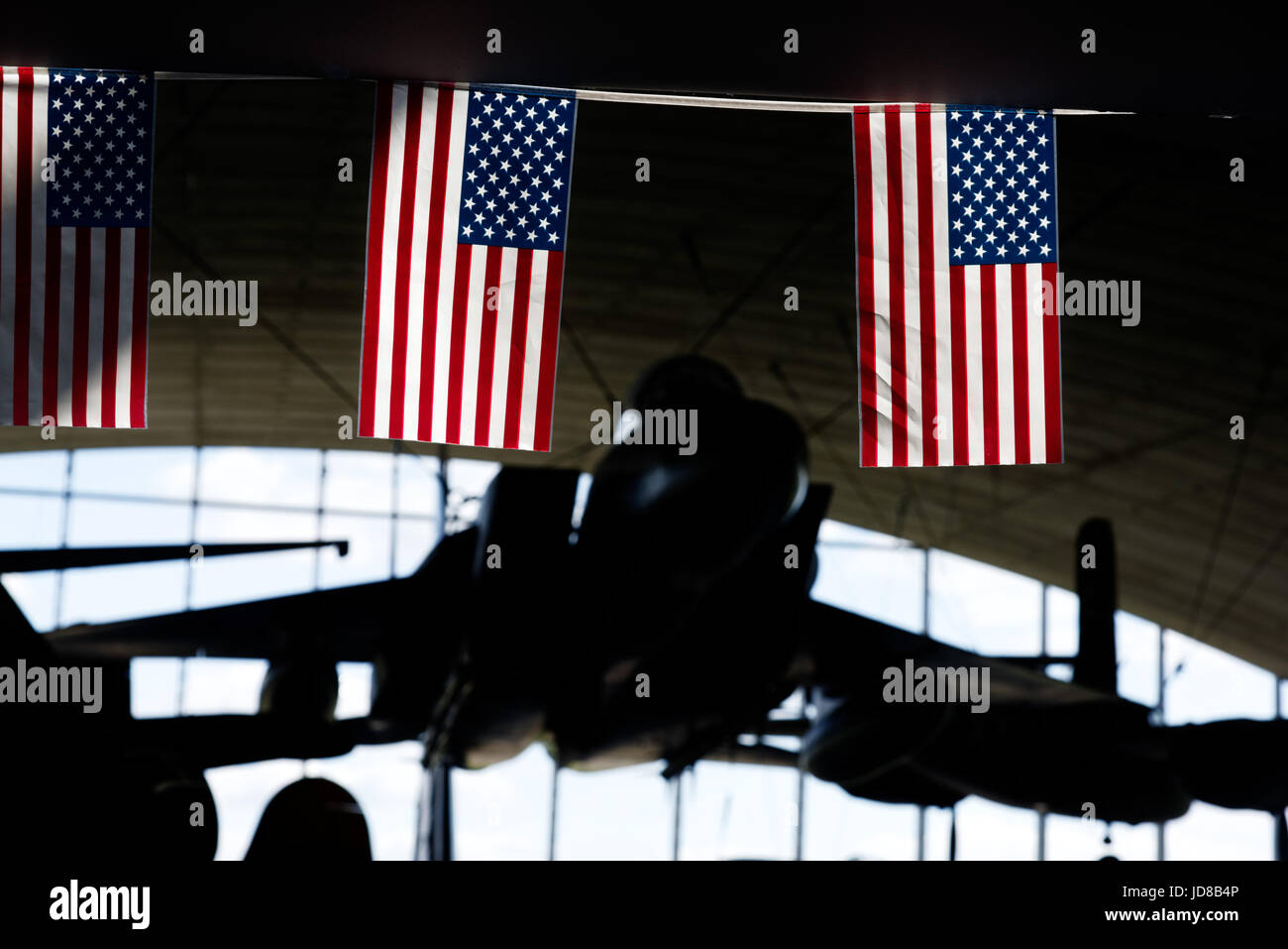 Duxford Air Museum in Cambridgeshie, England. The sun lights up the Stars & Stripes in the American Air Museum with the F-15 Eagle beyond. Stock Photo