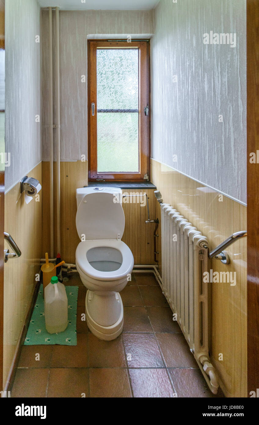Toilet With Seat Up In Small Narrow Bathroom With Window