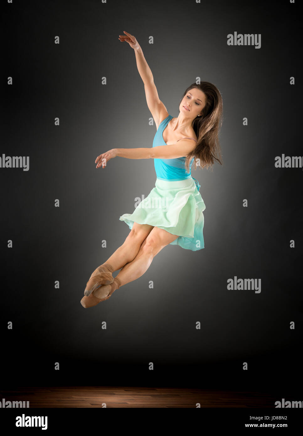 Female ballet dancer leaping mid air with legs in front, studio shot. caucasian fit pretty skinny athletic Stock Photo
