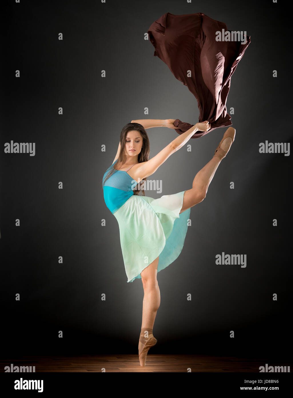 Female ballet dancer on one leg with fabric, studio shot. caucasian fit pretty skinny athletic Stock Photo