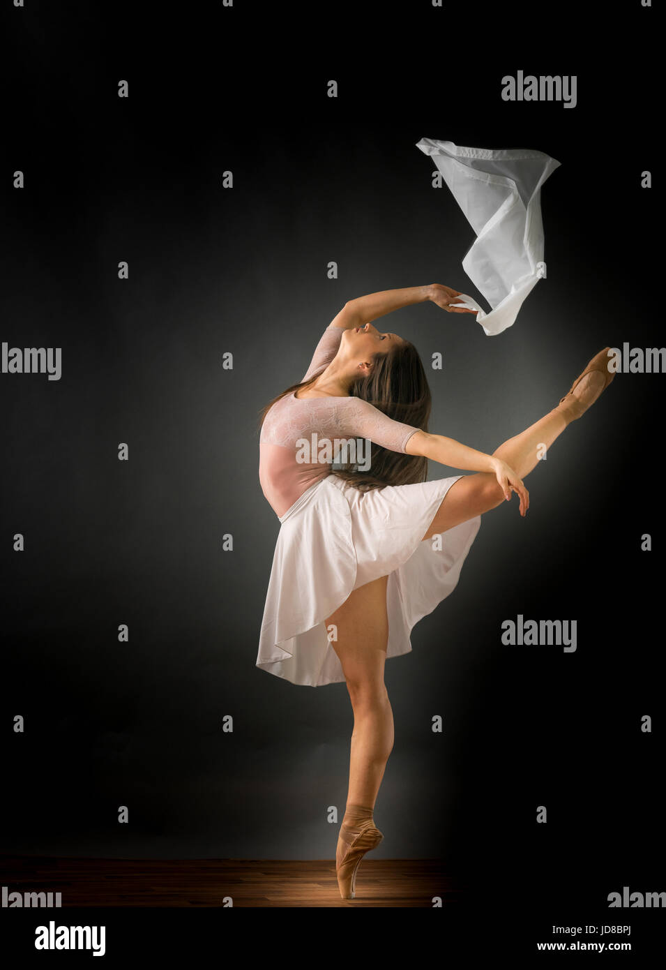 Female ballet dancer on one leg with fabric, studio shot. caucasian fit pretty skinny athletic Stock Photo