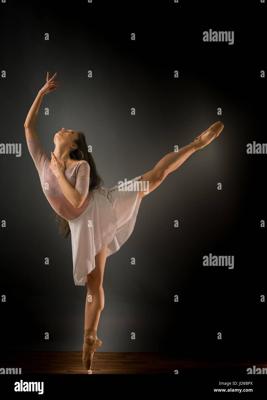 Female ballet dancer on one leg with arms stretched, studio shot. caucasian fit pretty skinny athletic Stock Photo