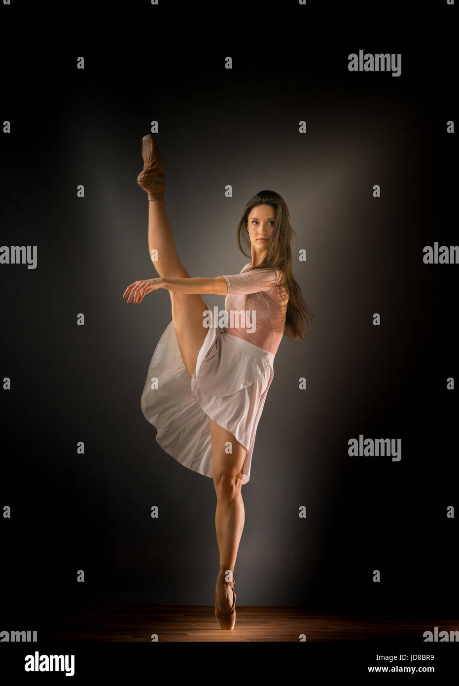 Female ballet dancer on one leg with arms stretched out in front, studio shot. caucasian fit pretty skinny athletic Stock Photo