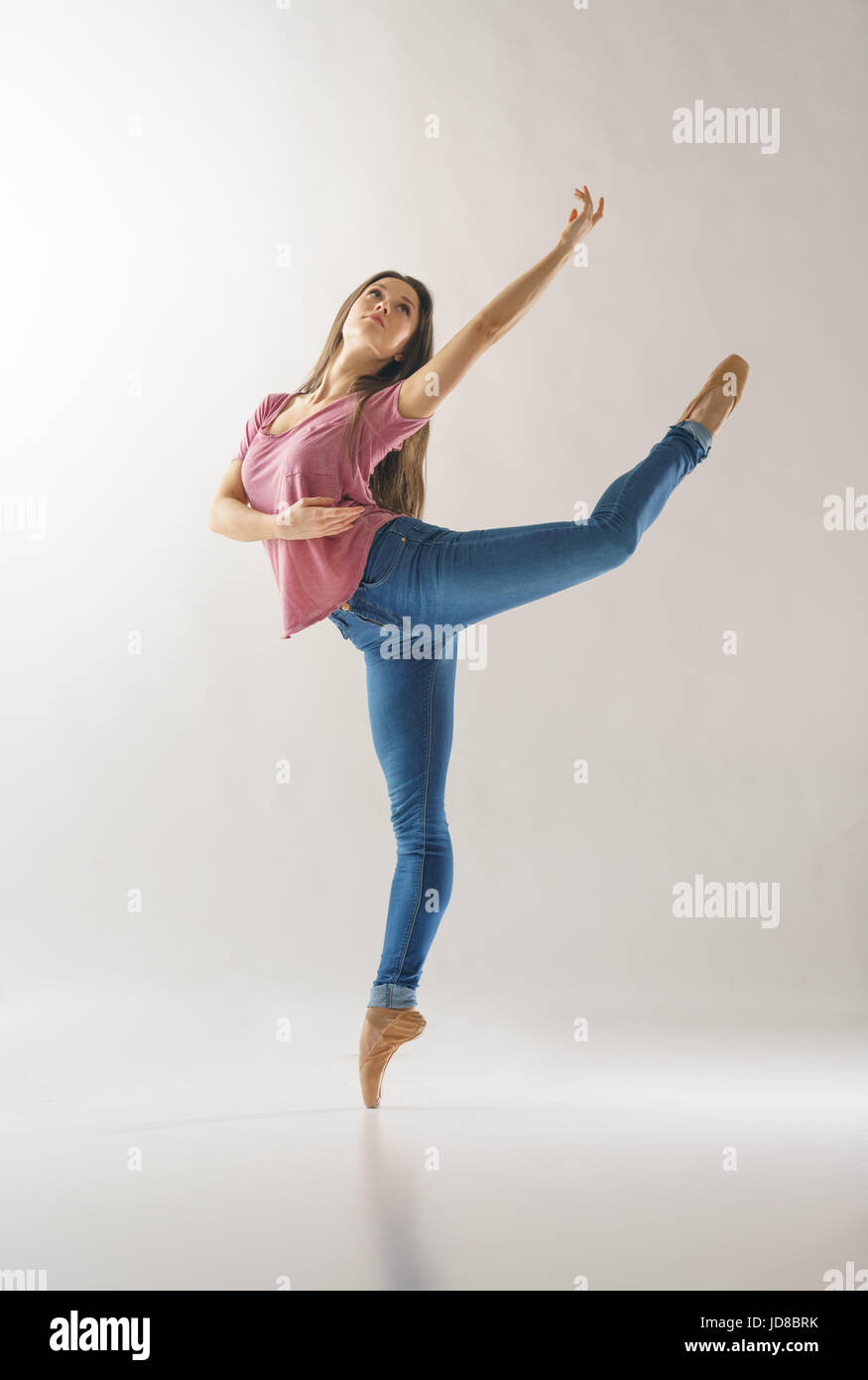 Female ballet dancer on one leg, wearing casual clothing, studio shot. caucasian fit pretty skinny athletic Stock Photo