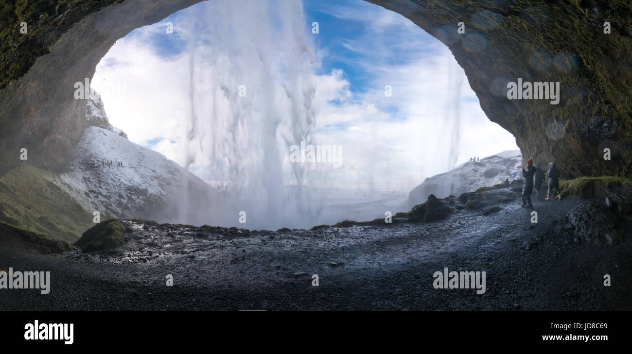 Tourists looking at view through cave at waterfall, Iceland, Europe. Iceland nature 2017 winter cold Stock Photo
