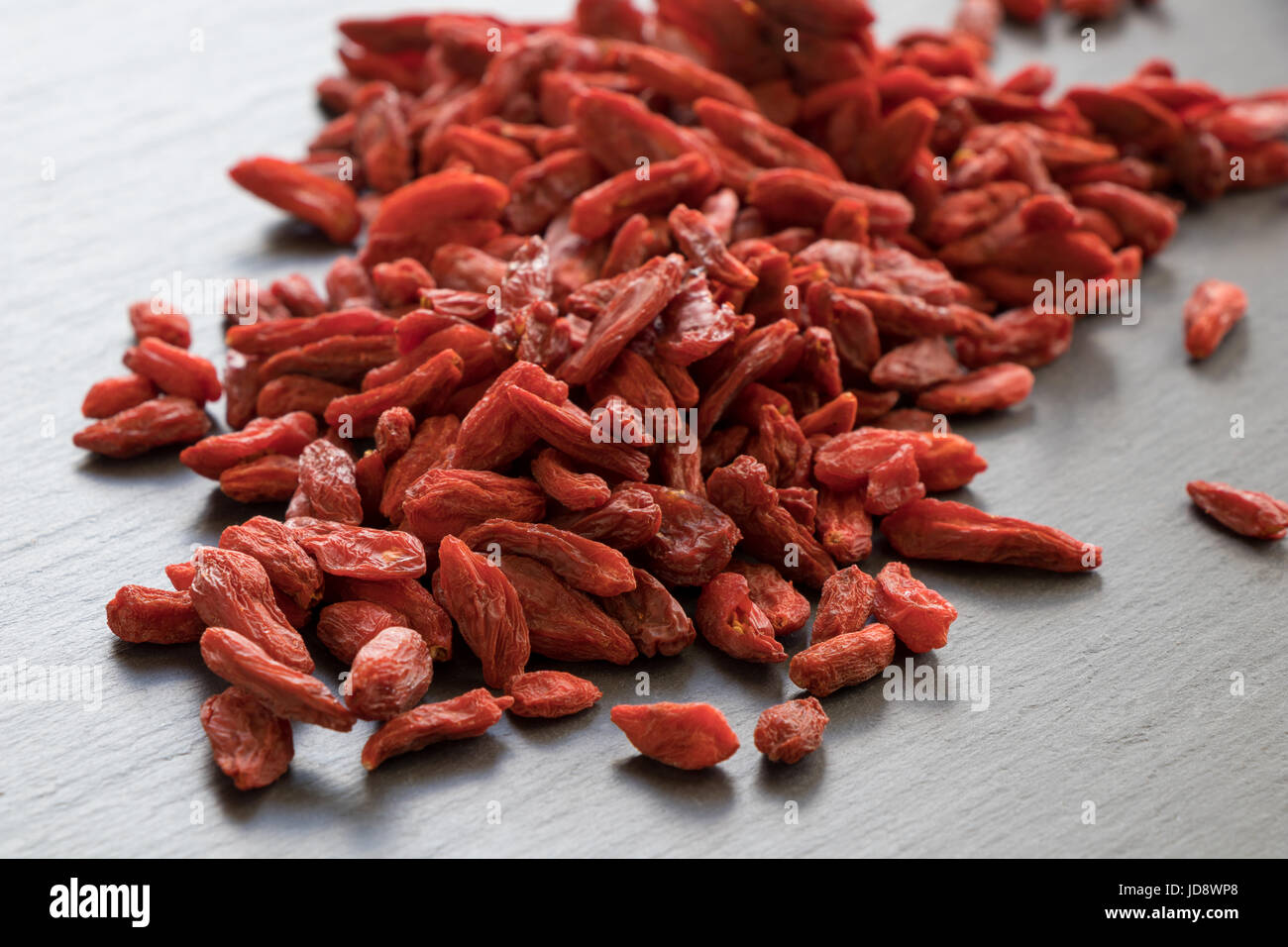 A pile of dried goji berries on a stone background. Stock Photo