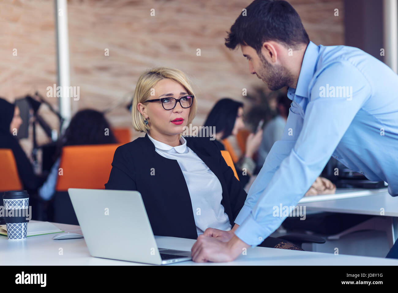 Colleagues chatting, sitting together at office table, smiling Stock ...