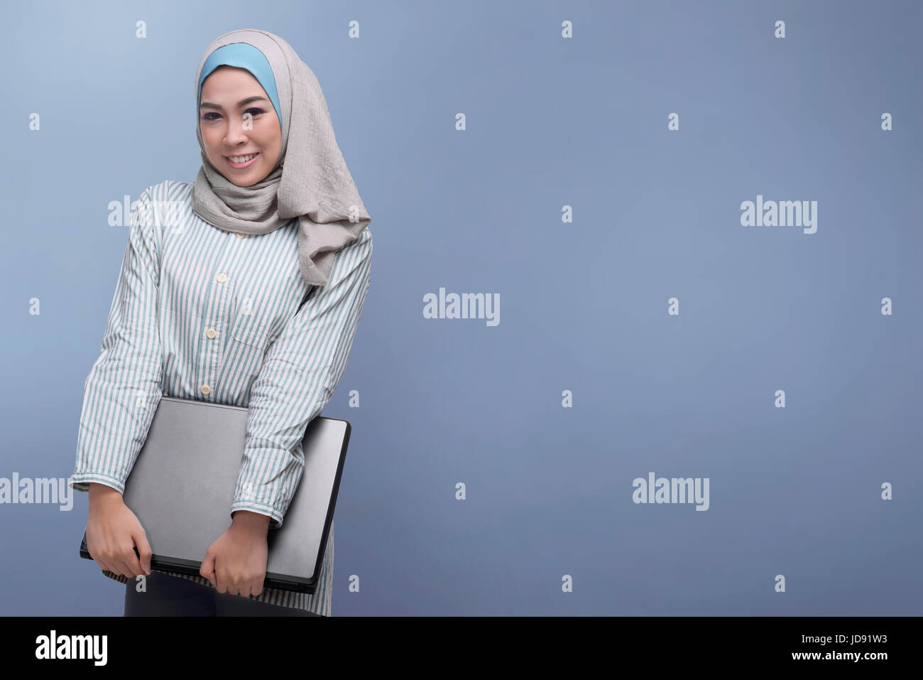 Young asian muslim woman holding laptop against bright background Stock ...