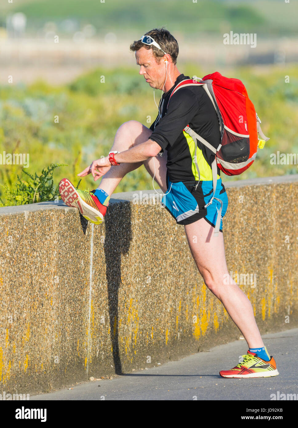 Man stretching and exercising in the early morning on a hot summers morning. Stock Photo