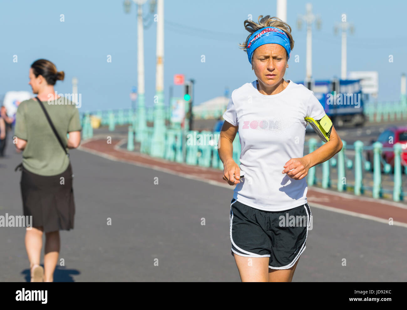 Woman jogging along a seafont promenade on a hot summers morning. Stock Photo