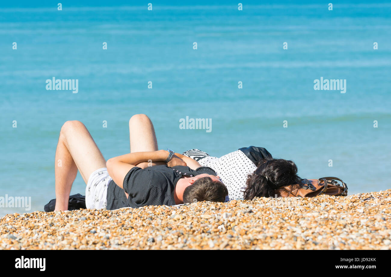 Couple laying in the sun on a shingle beach in Summer. Stock Photo