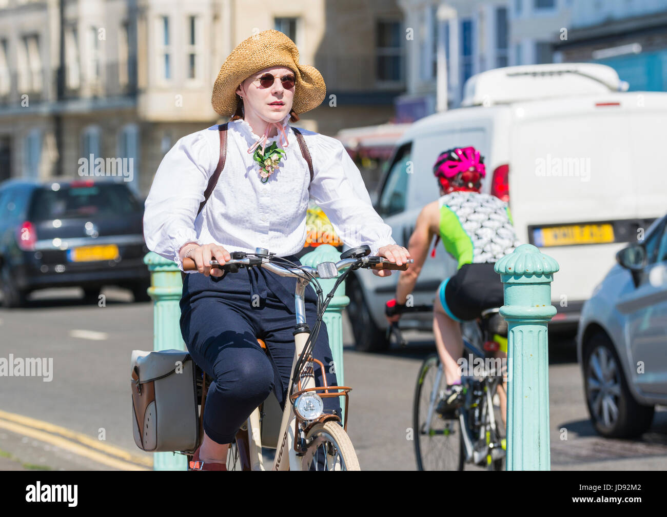 Lady cycling along a cycle lane in Summer, wearing a Summer hat. Lifestyle concept. Stock Photo