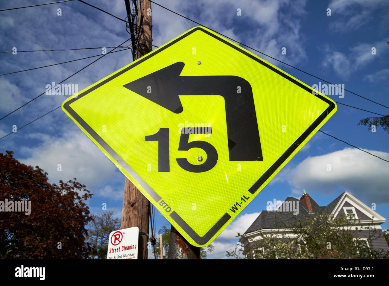 bright yellow diamond warning sign 15 miles per hour bend ahead dorchester Boston USA Stock Photo