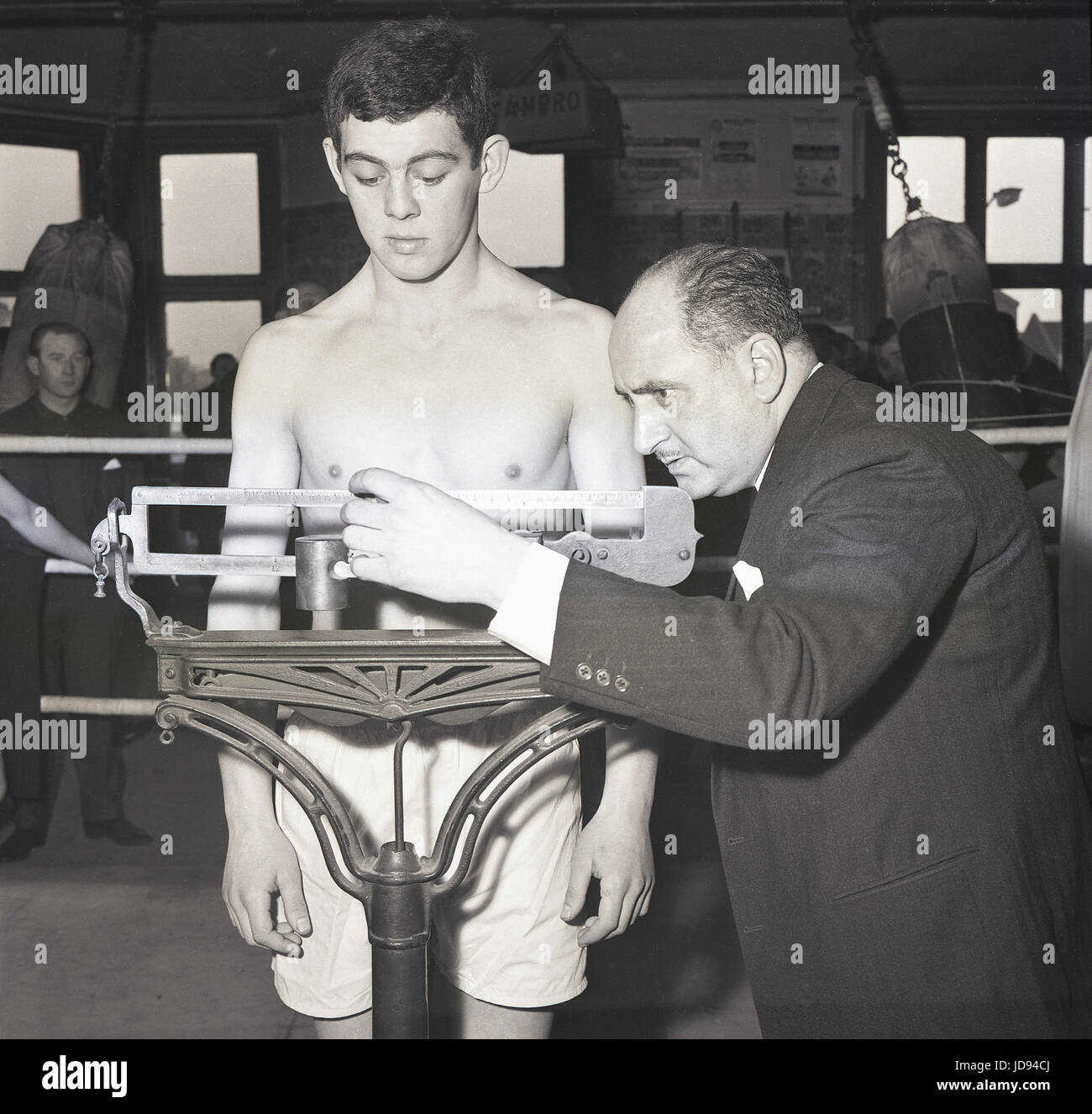 1964, the gym at the famous Thomas A Beckett public house on the Old Kent Road, Bermondsey, South London, SE1, England, picture shows a boxer in a ring being officially weighed in on mechanical scales before the contest. Stock Photo