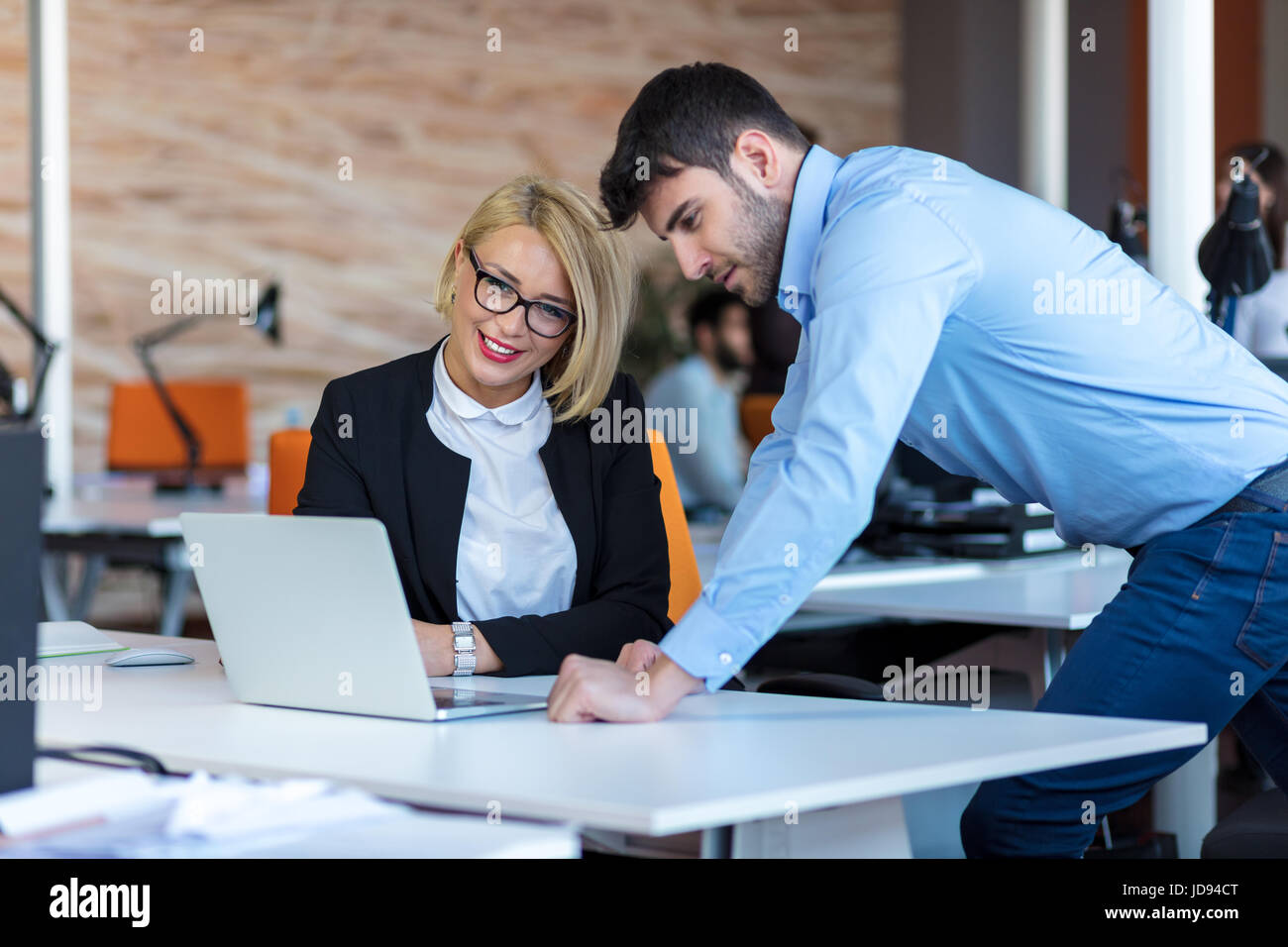 Colleagues chatting, sitting together at office table, smiling Stock ...