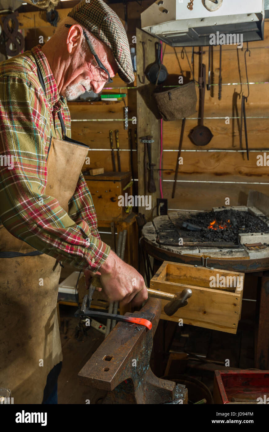 Blacksmith Hammering and Shaping Steel On Anvil Stock Photo