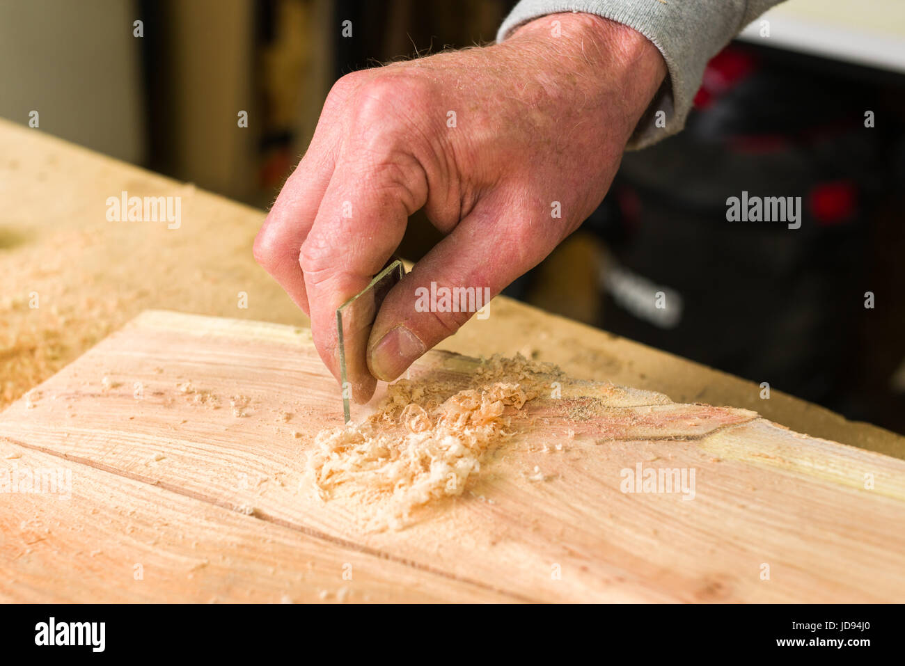 Woodworker Smoothing Wood With Glass In Workshop Stock Photo