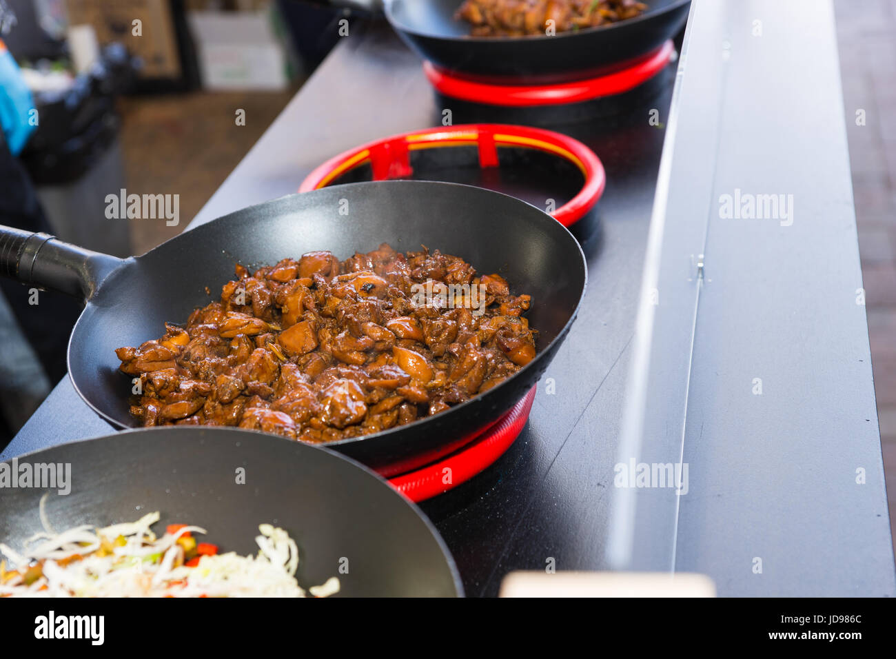 https://c8.alamy.com/comp/JD986C/row-of-woks-with-freshly-cooked-food-on-portable-heating-devices-at-JD986C.jpg