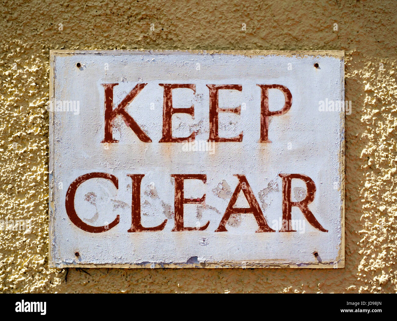 Fading Keep Clear sign mounted to pebbledash wall. Stock Photo