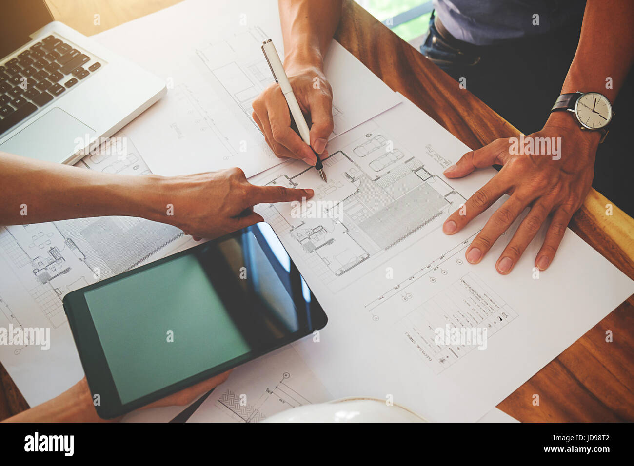 Architects engineer discussing at the table with blueprint - Closeup on hands and project print. Stock Photo