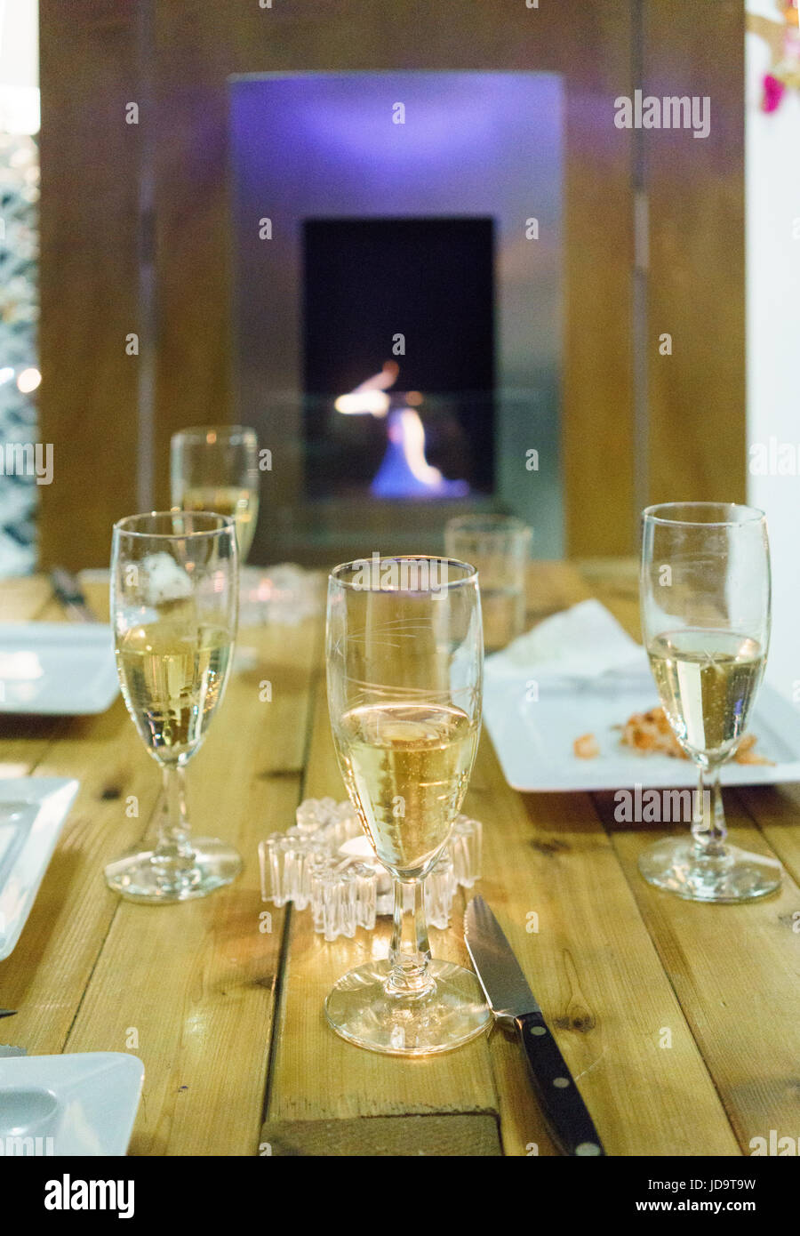 Place settings on table with champagne glasses, fire in background Stock Photo
