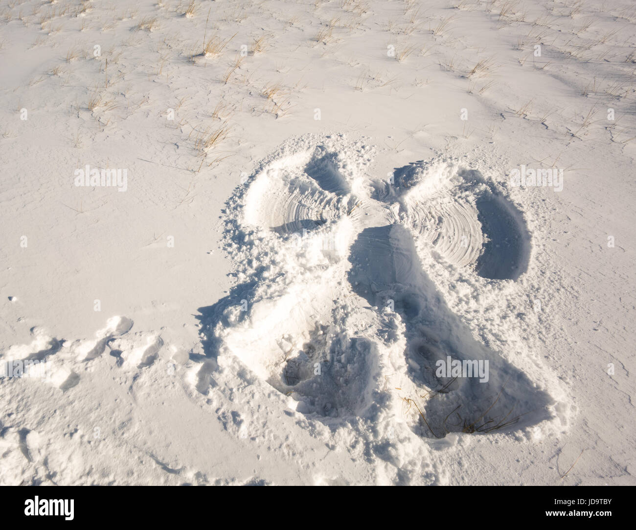 Freshly made snow angel imprint in snow, footprints leading away from impriknt, elevated view  ontario canada winter cold 2017 snow Stock Photo