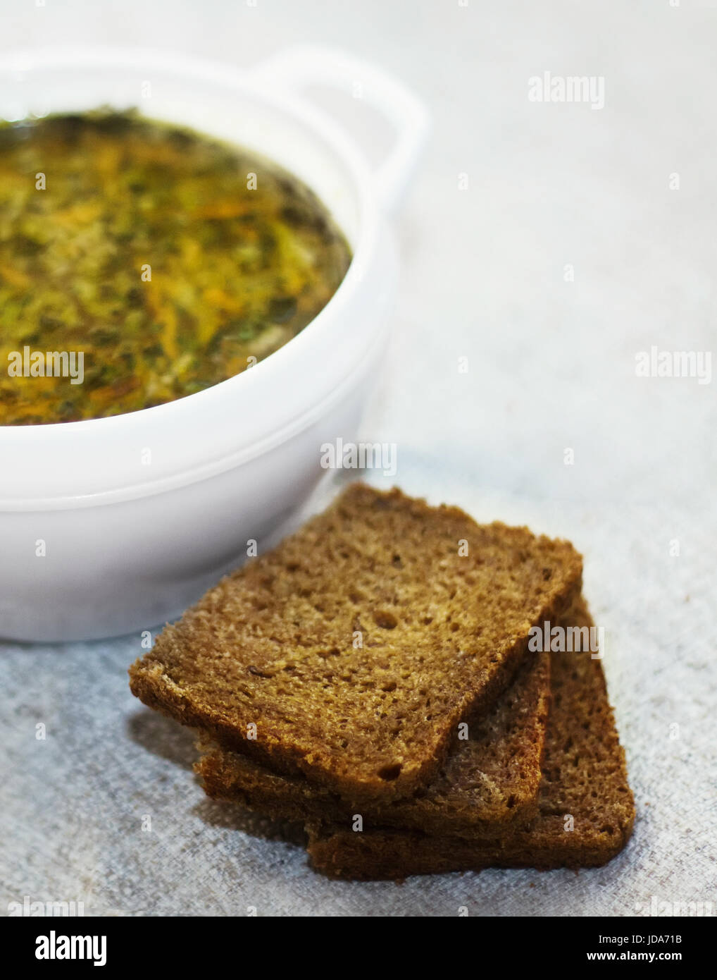 Bowl of vegetable soup and three pieces of bread on a table. Stock Photo