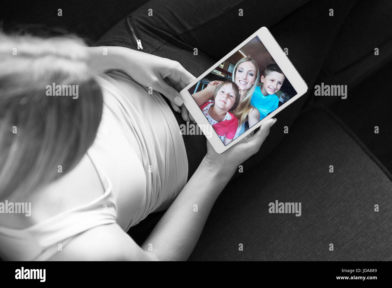 Blonde Woman Sitting On A Sofa Using Her Tablet Stock Photo - Alamy