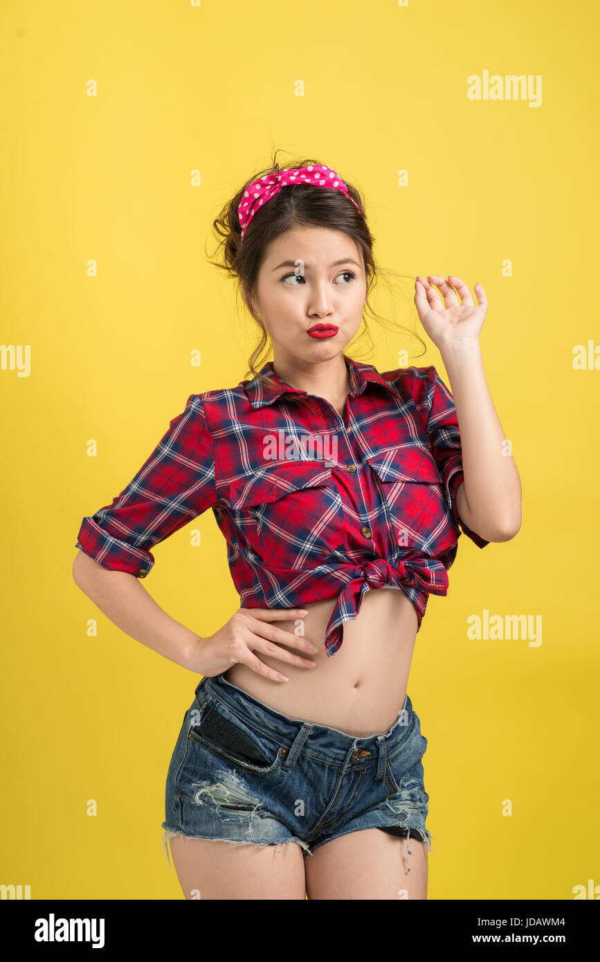 Asian Woman Retro Portrait With Pin Up Make Up And Hairstyle Posing Over Yellow Background Stock