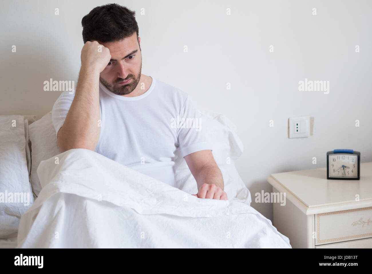 Sad and upset man waking up in the morning light Stock Photo