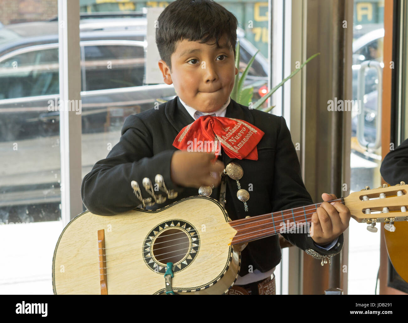 A young teenage member of the A.M.N.A. mariachi bands performs on his guitar at a Mexican restaurant opening in North Corona, Queens, New York City. Stock Photo