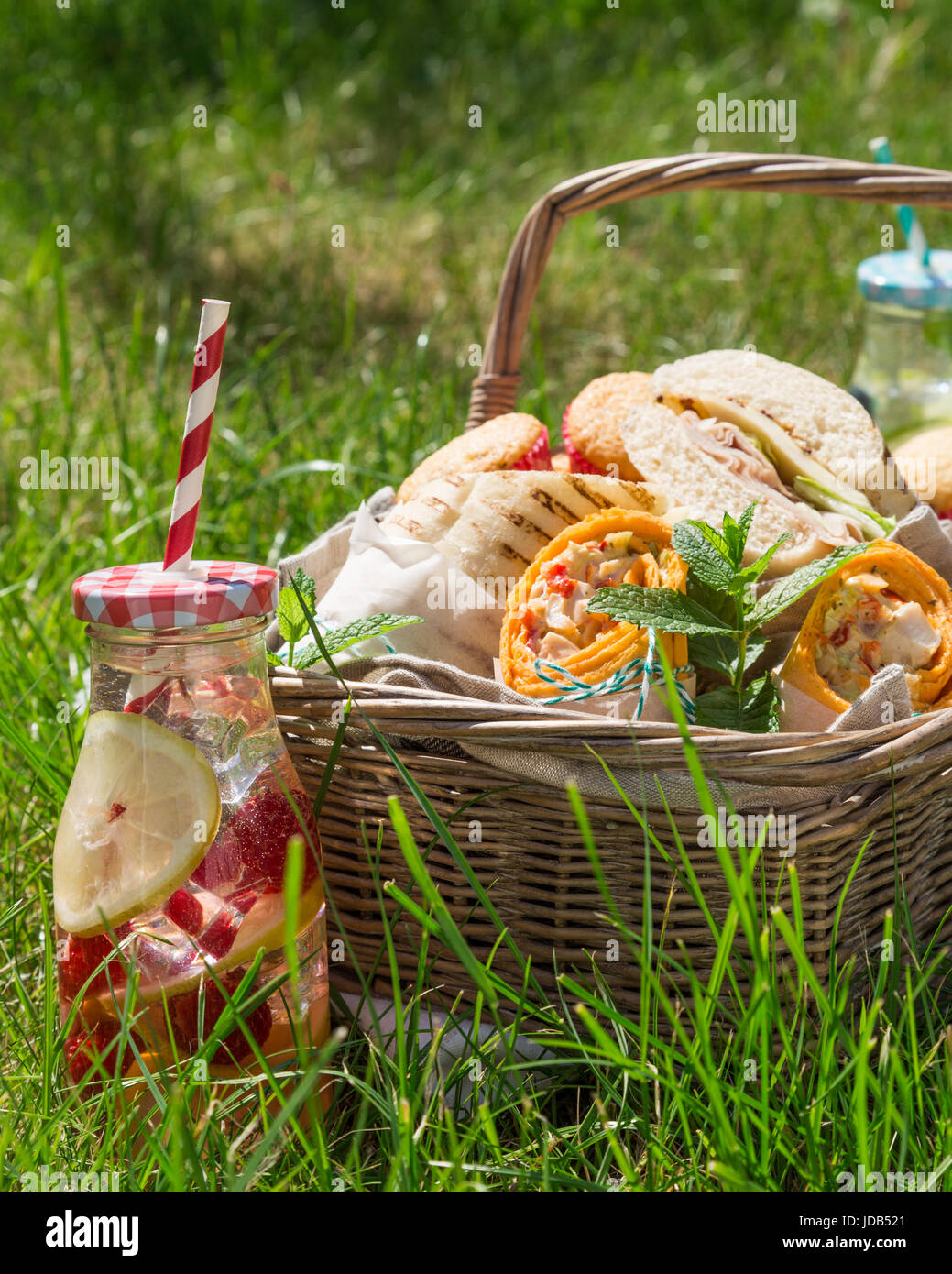 Picnic basket with food on green sunny lawn Stock Photo