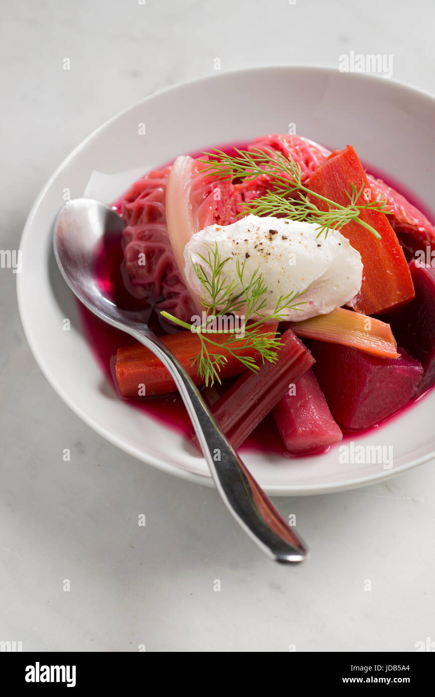 One plate of Ukrainian red bortsch soup with a spoon on a white background. Close-up. Traditional plate with beetroot and vegetables. Stock Photo