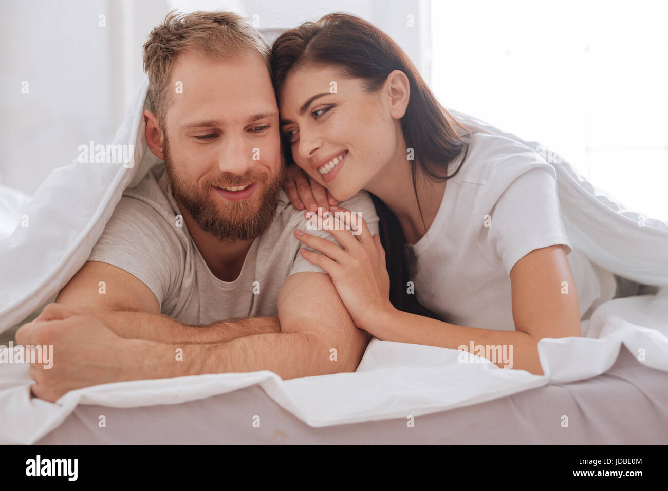 Lovely Couple Having Pillow Talk Underneath Blanket Stock Photo