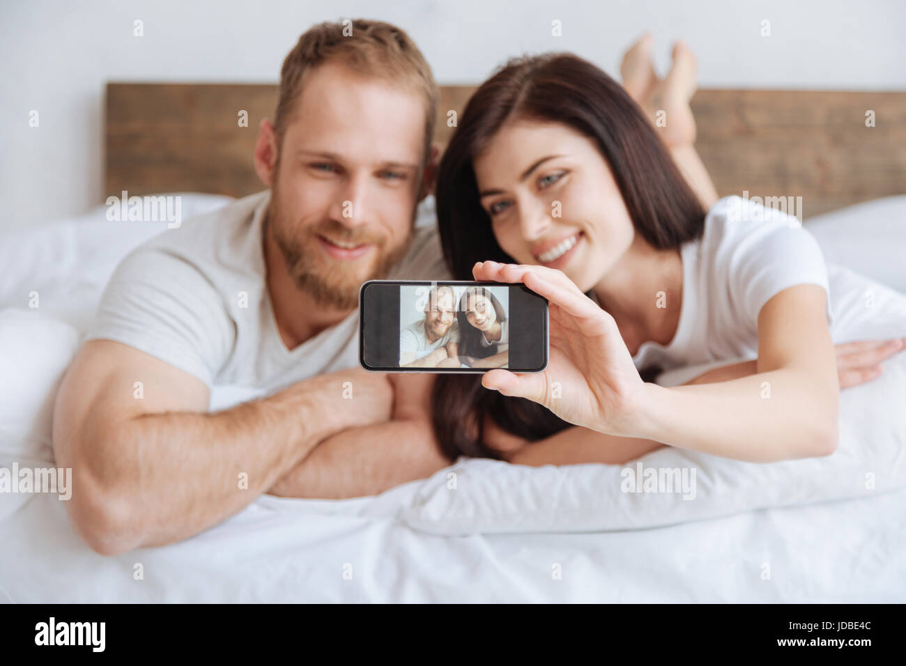 Portrait of newly married couple taking selfie in bed Stock Photo