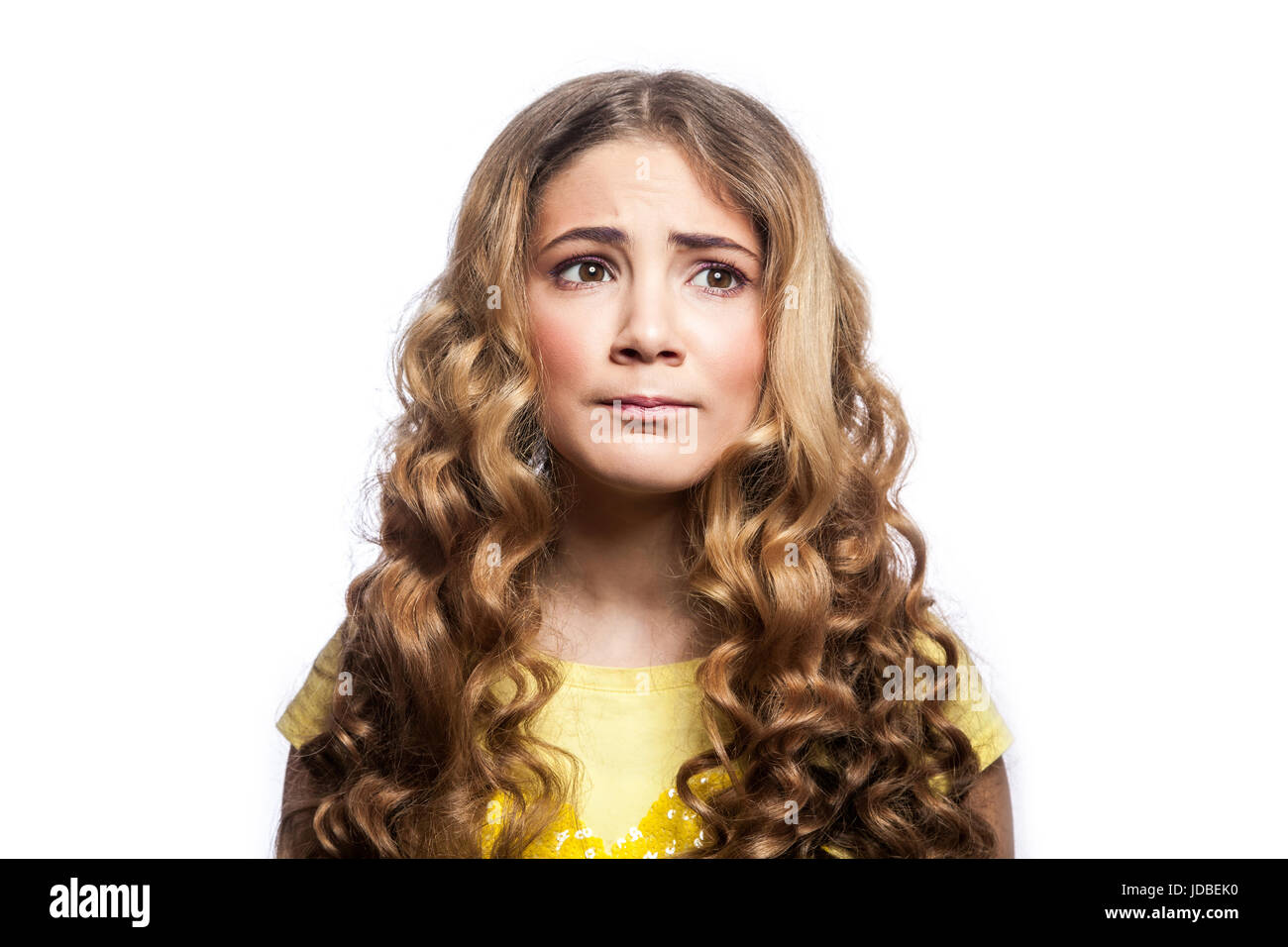 Portrait of thoughtful girl with wavy hairstyle and yellow t shirt. studio shot isolated on white background. Stock Photo