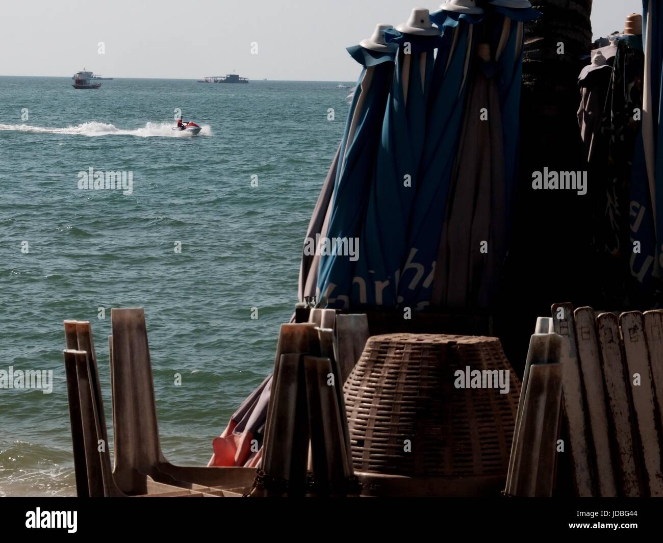 jet ski boats Basket chairs beach umbrella stacked on beach Pattaya