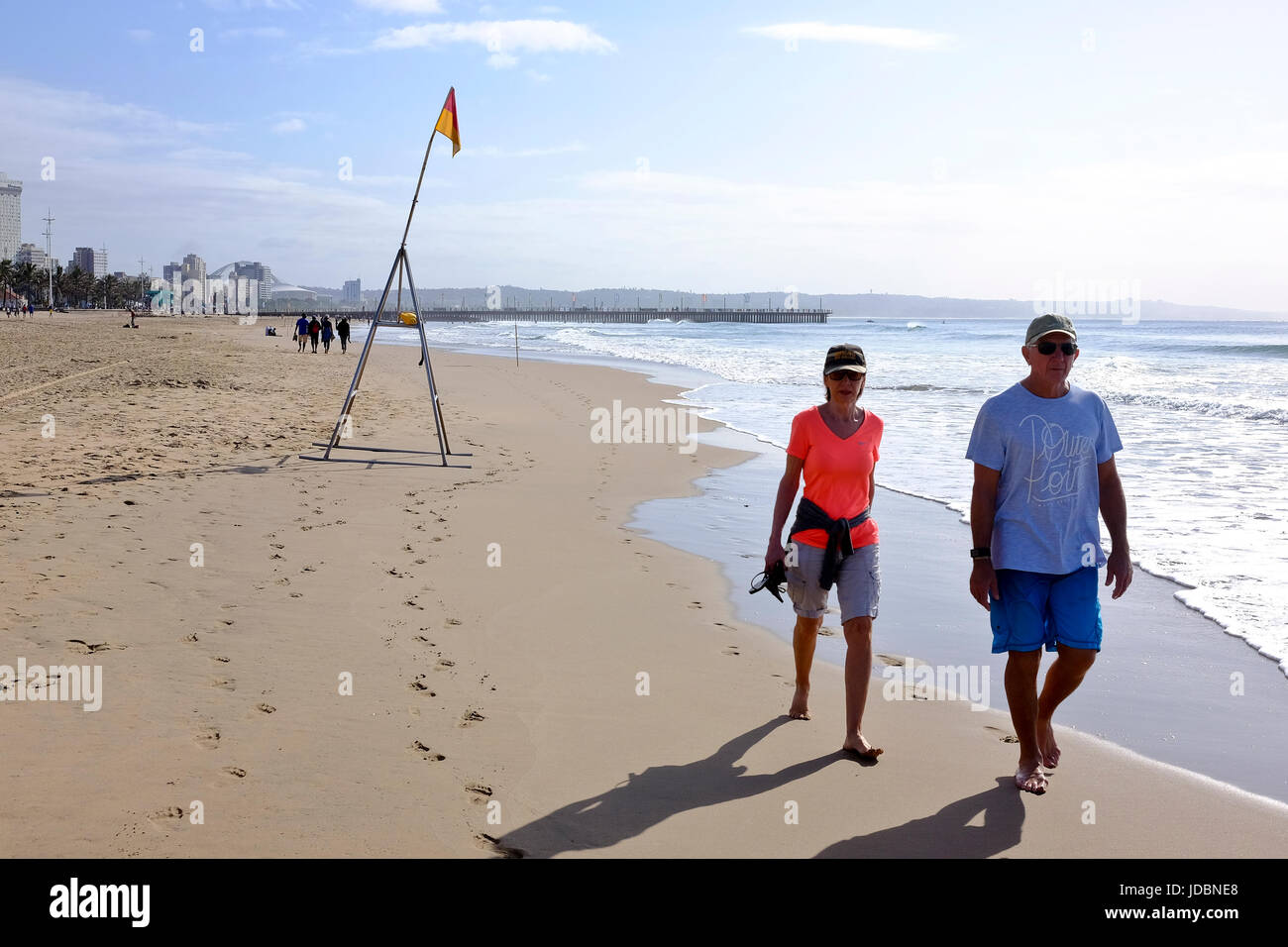 Durban South Africa. A couple walk barefoot along a beach enjoying the